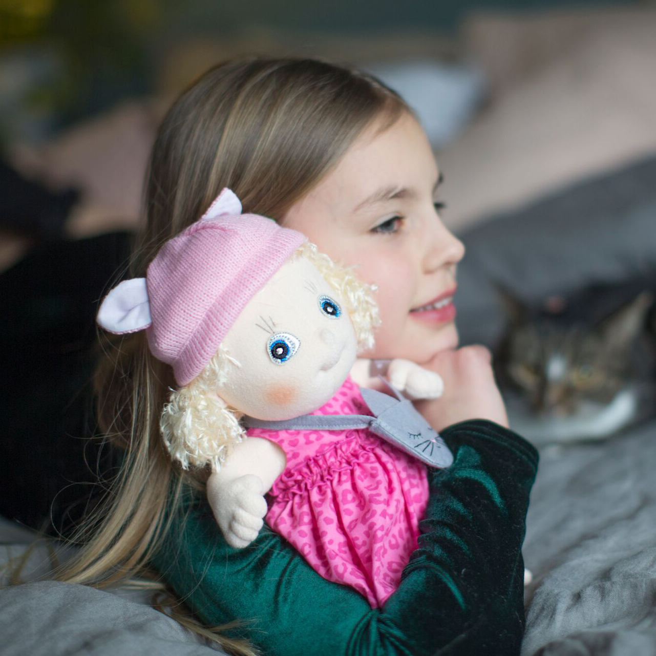 Kind kuschelt mit der Rubens Cutie Puppe Emelie auf dem Bett