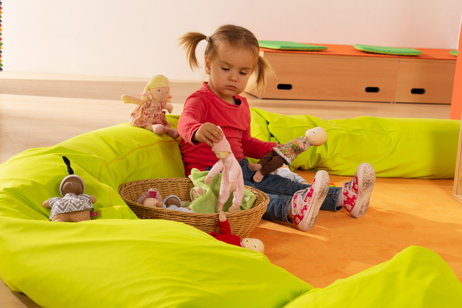 Toddler playing with the small fabric dolls from the Joyk Treasure Basket set