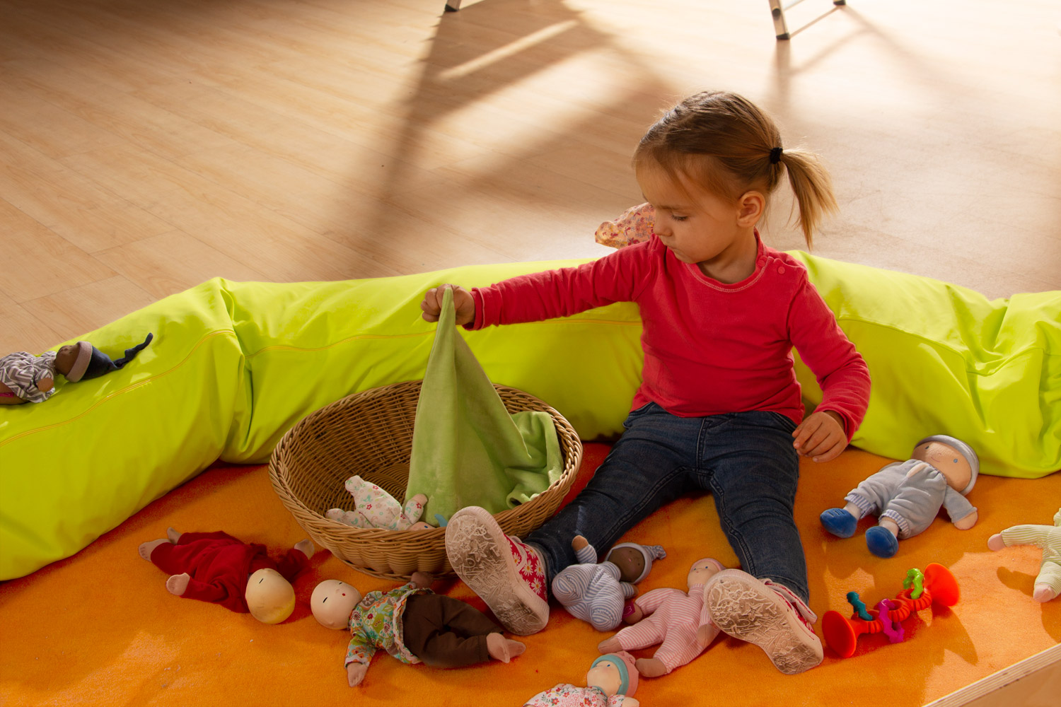Child tucking in the fabric dolls from the Joyk Treasure Basket set with a cloth