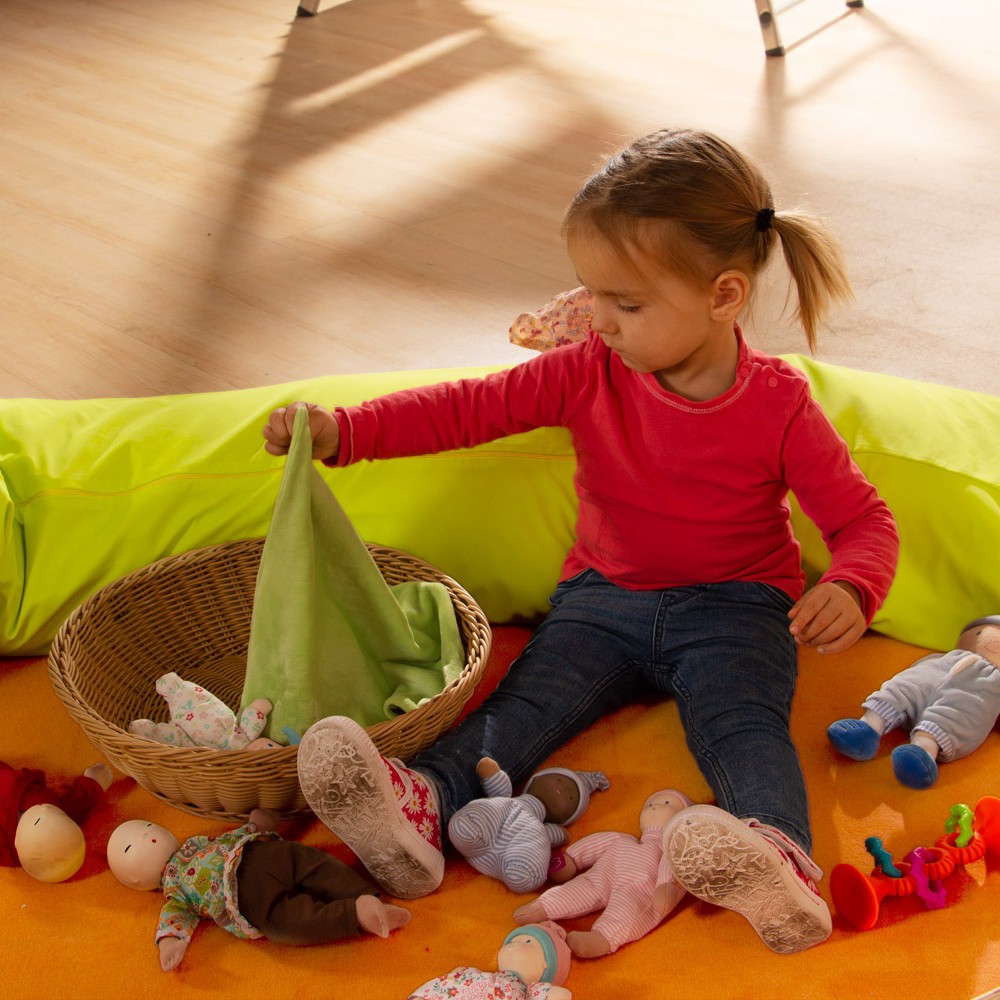 Child tucking in the fabric dolls from the Joyk Treasure Basket set with a cloth