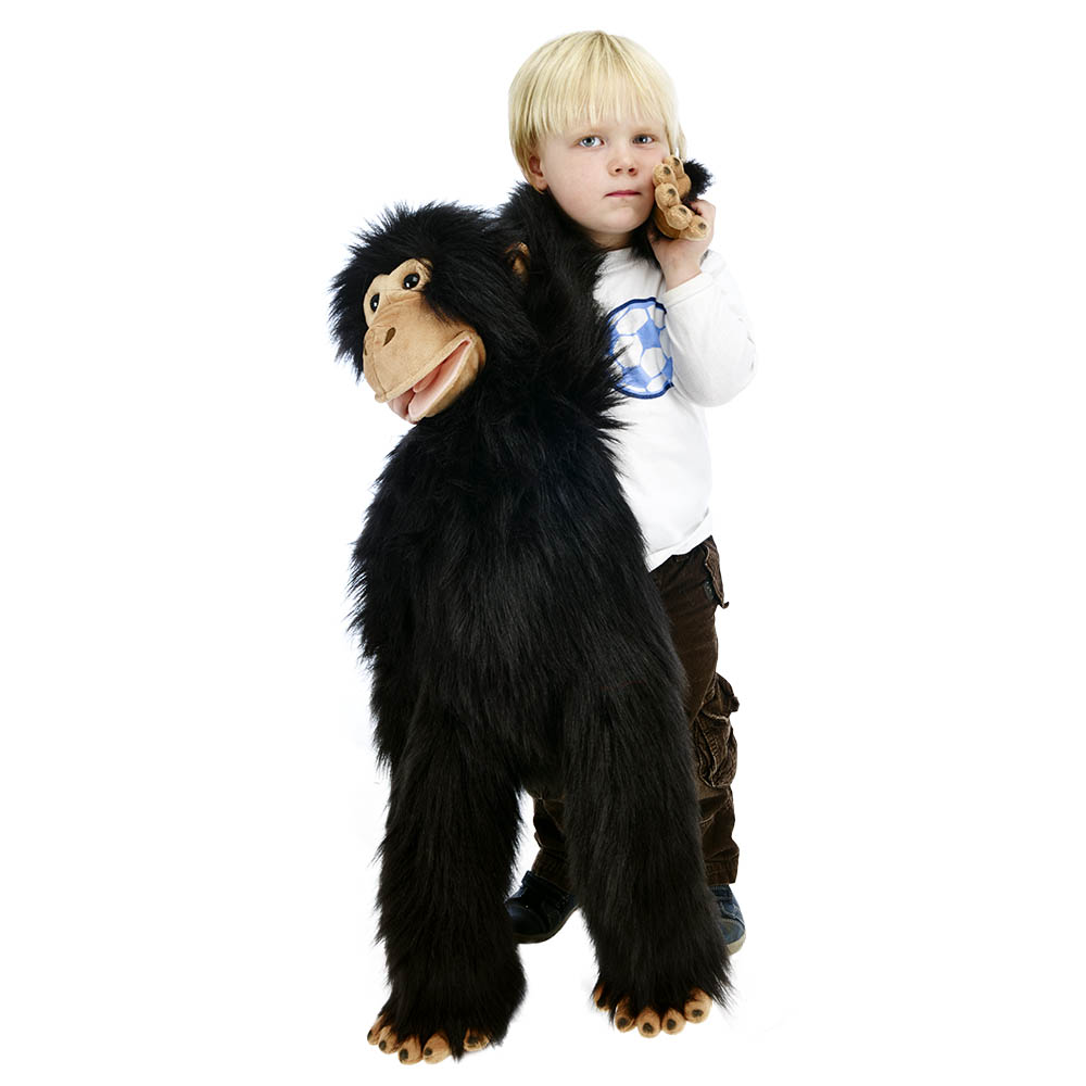 Boy on the phone eating a cookie with the The Puppet Company giant chimpanzee hand puppet on his shoulder, usage example