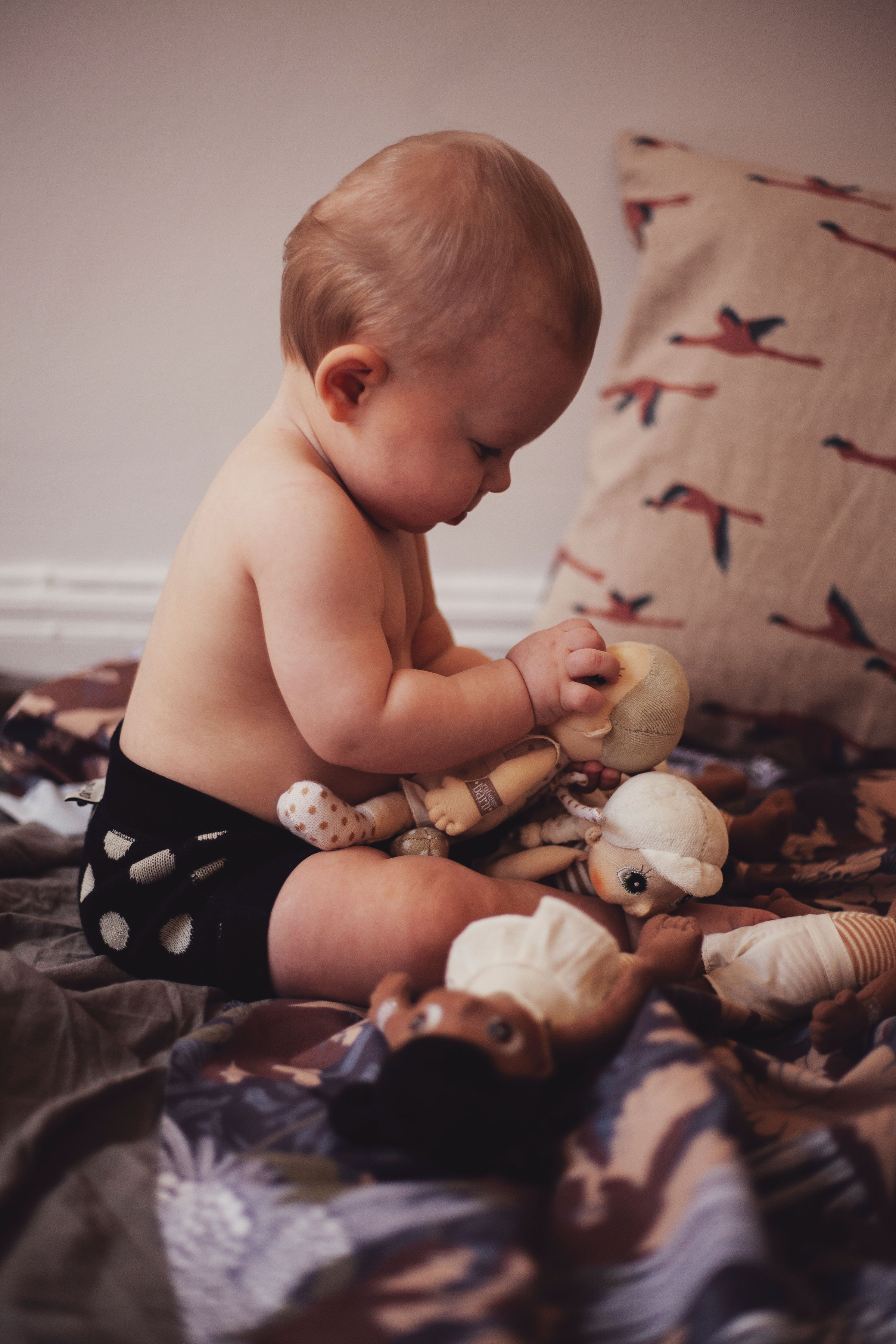 Baby looking at a Rubens EcoBuds mini doll while playing
