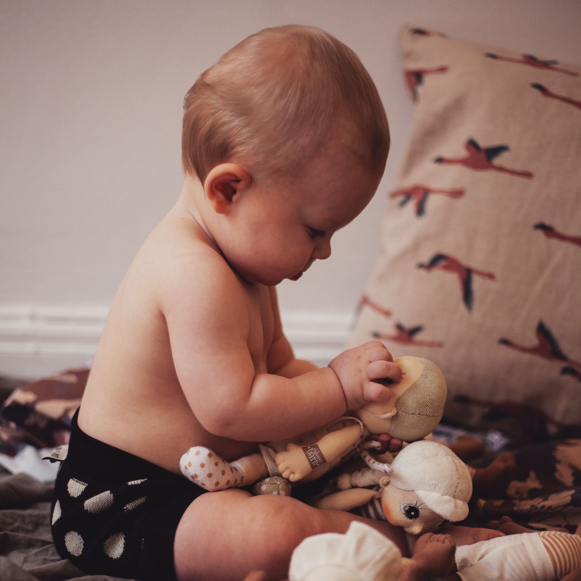Baby betrachtet eine Rubens EcoBuds Mini-Puppe beim Spielen