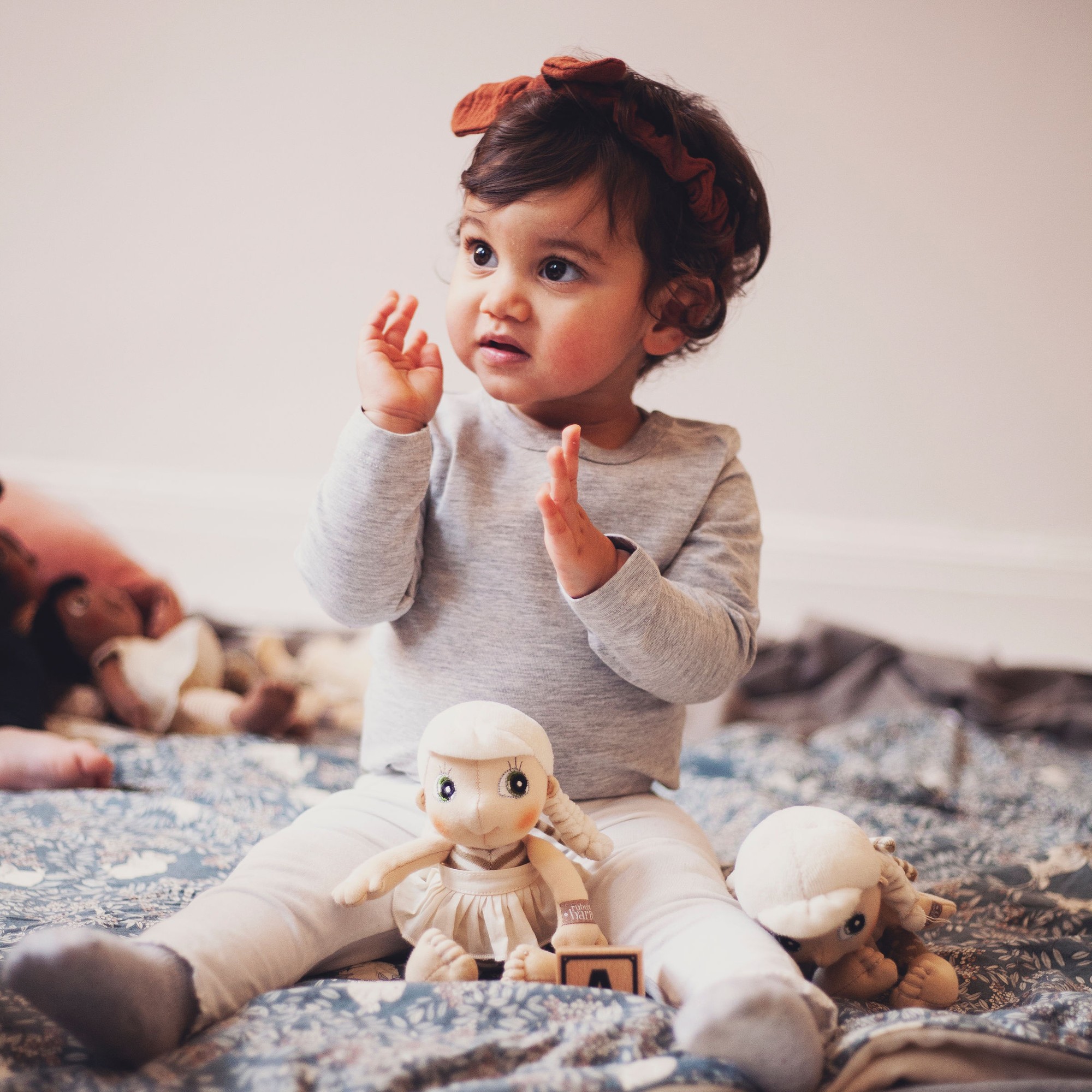 Kleinkind spielt mit der Rubens EcoBuds Mini-Puppe Lily auf einer Decke