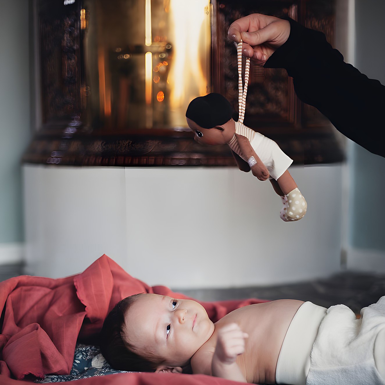 Die Rubens EcoBuds Mini-Puppe Basil wird einem liegenden Baby gereicht