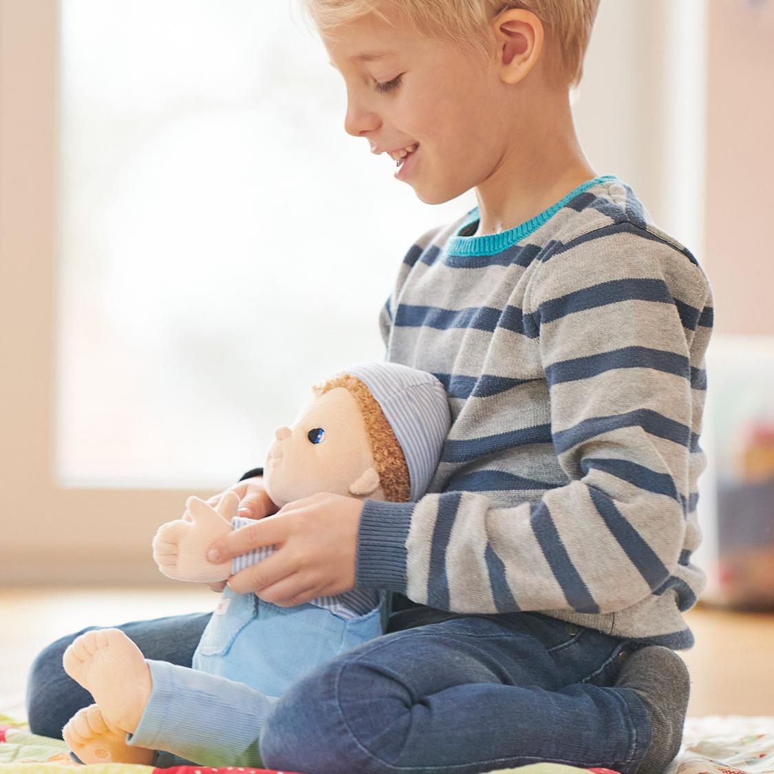 Child playing with the Joyk empathy doll Baby Jack on a play blanket