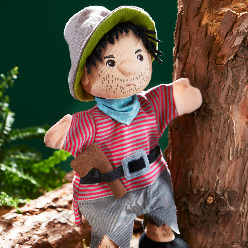 HABA Baby-Handpuppe Räuber, Anwendungsfoto im Wald an einem Baumstamm