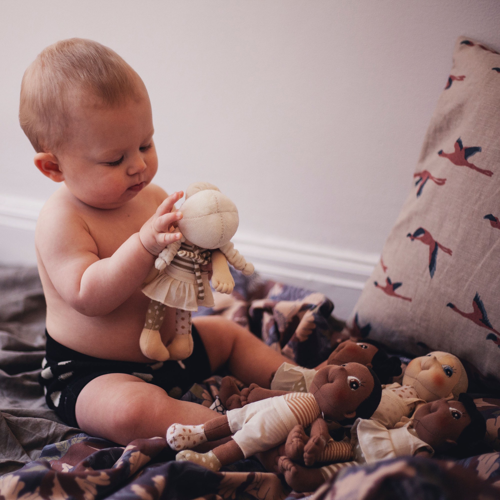 Baby spielt mit einer Rubens EcoBuds Mini-Puppe auf einer Decke