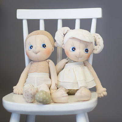Rubens EcoBuds dolls Aspen and Daisy sitting next to each other on a white children's chair