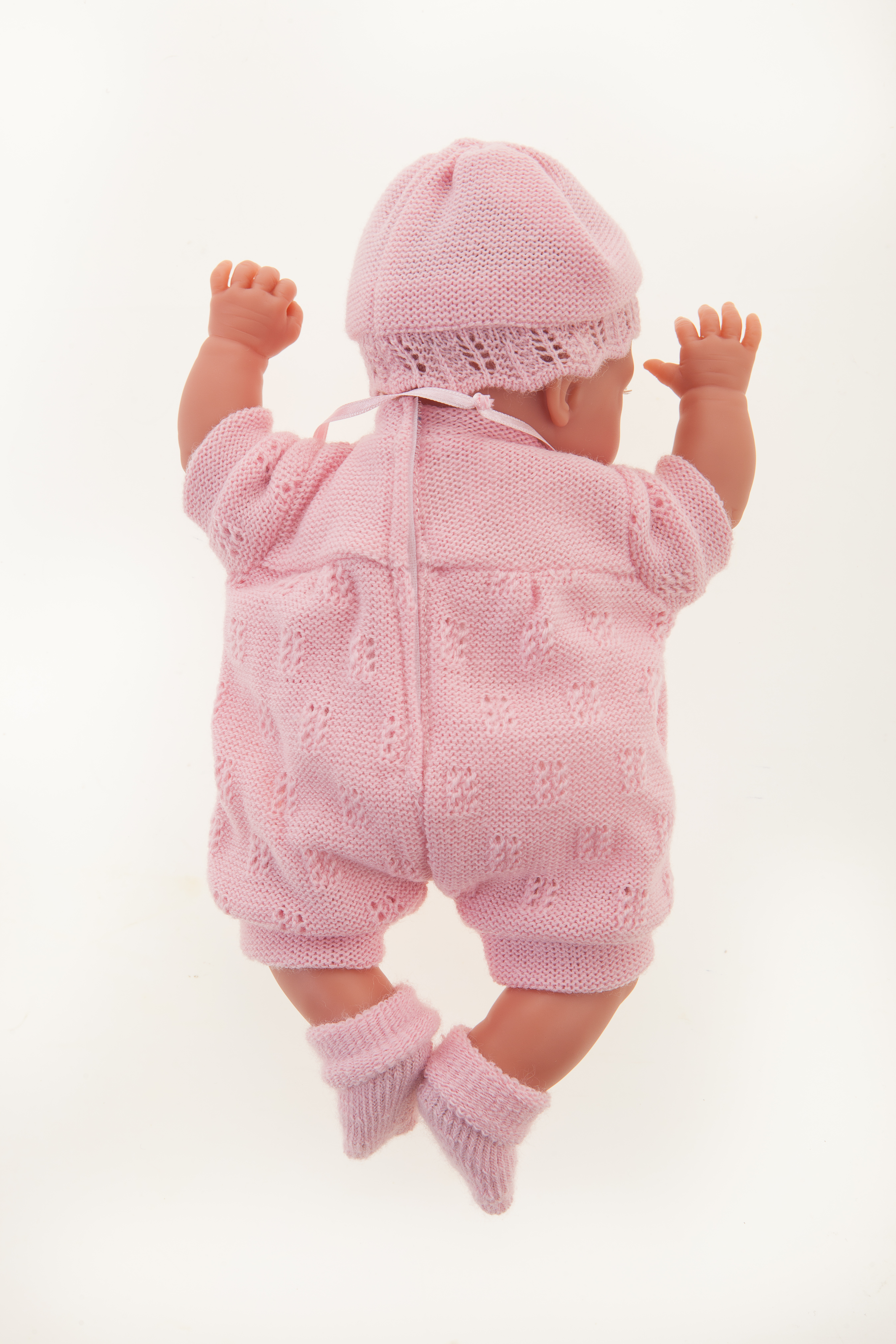 Antonio Juan baby doll Peke, realistic doll in a pink knit outfit seen from behind, both arms stretched upward