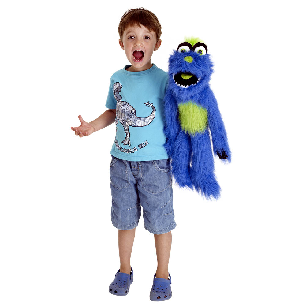 Boy posing and shouting next to the The Puppet Company blue-green monster hand puppet, usage example