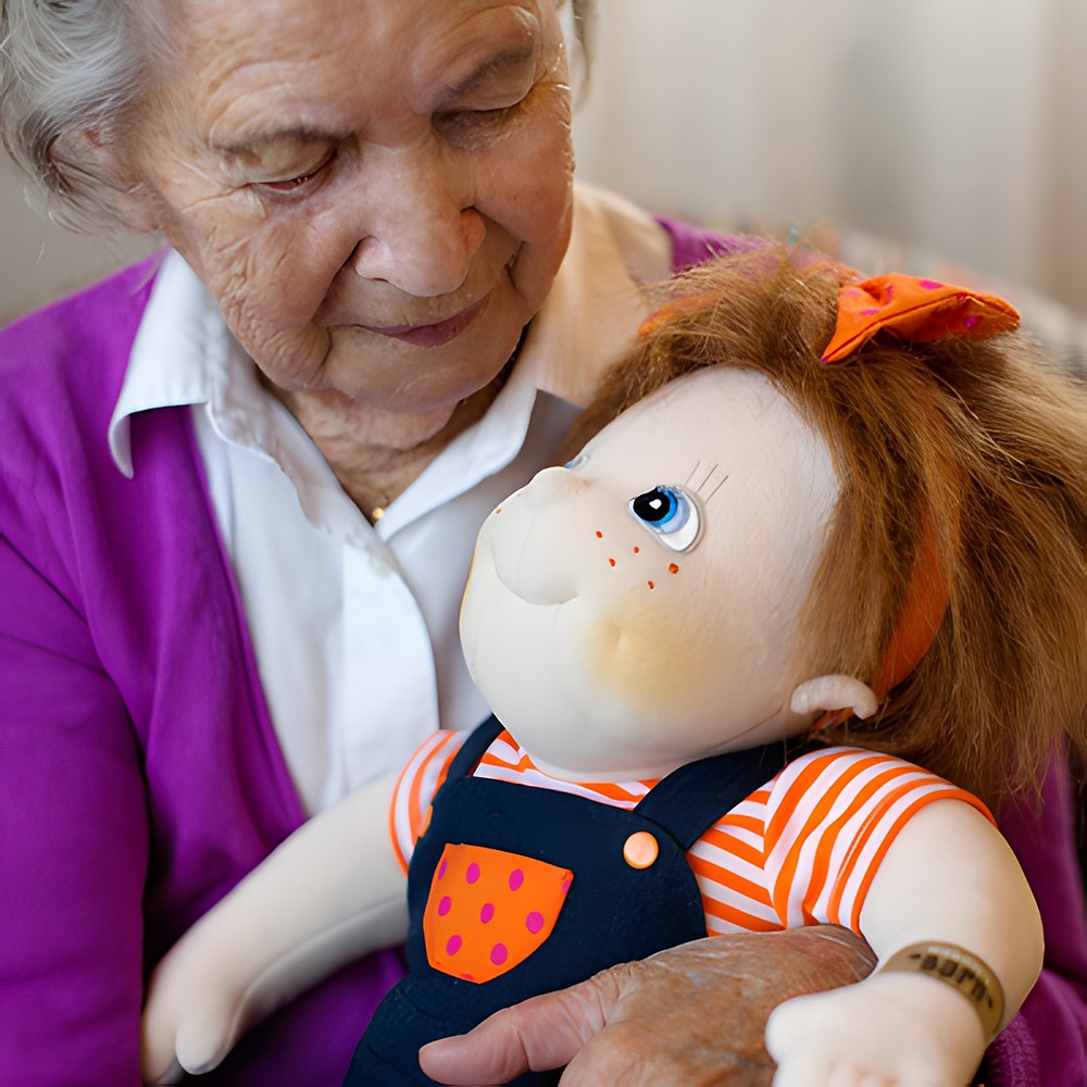 Seniorin hält die Rubens Barn Original-Puppe Anna im Arm