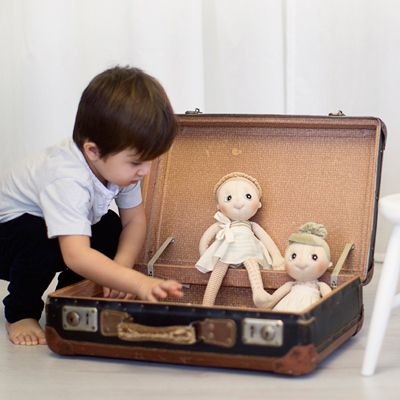 Kind packt die Rubens EcoBuds Puppen aus einem alten Reisekoffer aus