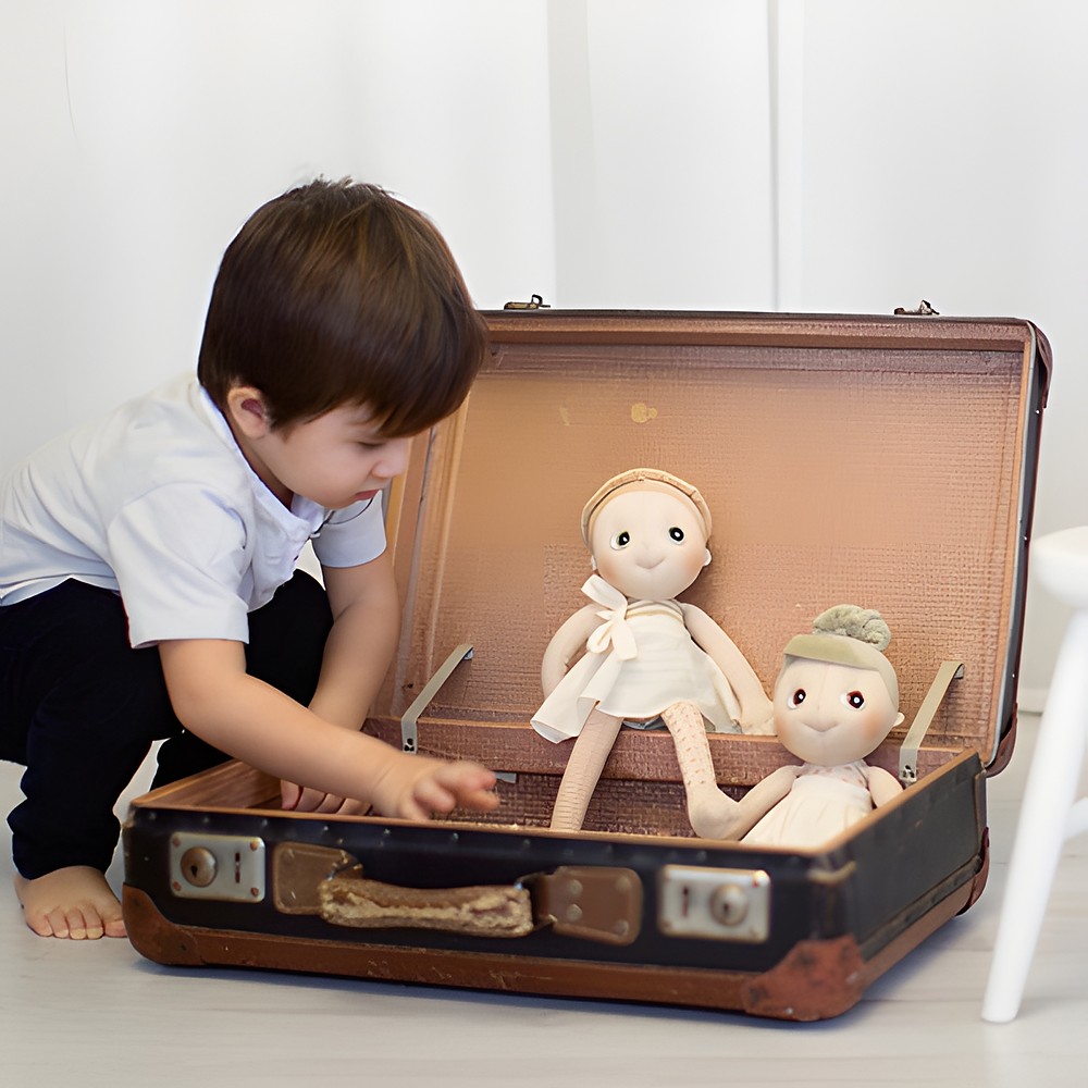 Kind packt die Rubens EcoBuds Puppen aus einem alten Reisekoffer aus