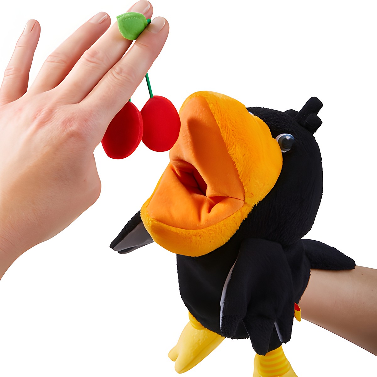 HABA Baby-Handpuppe Rabe Theo, Nahaufnahme einer Hand, die dem Raben Plüsch-Kirschen ans Maul hält