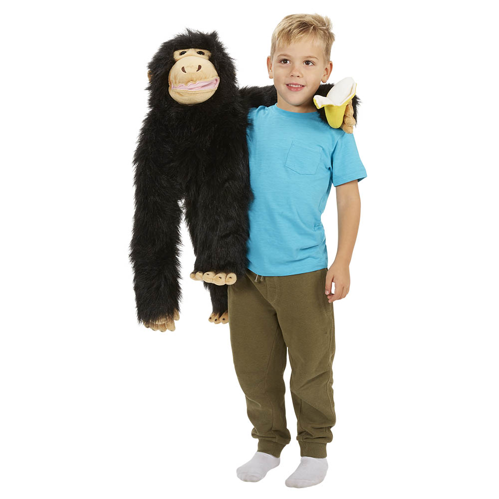 Boy holding the The Puppet Company giant chimpanzee hand puppet with a banana in his arms, usage example