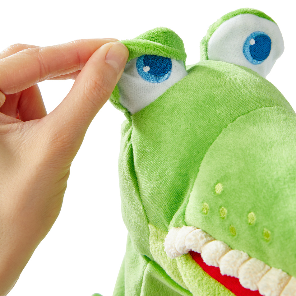 HABA baby hand puppet crocodile Allesfresser, close-up of a hand lifting the movable eyelid